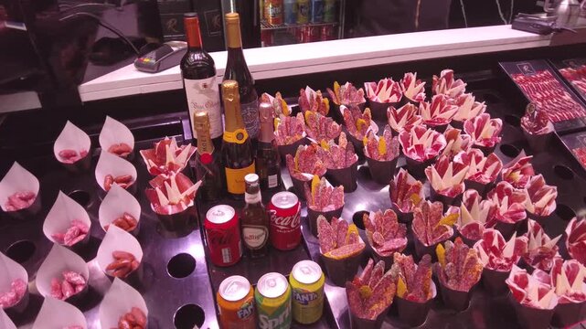 Close up of vine and spanish ham at a large market hall in Spain, Barcelona, Panning across  the snacks