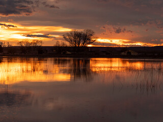 Obraz premium Sunset over the pool in Loreto, Huesca with golden reflections and colorful sky. Ideal image for tourism, summer and relaxation concepts in Spain.
