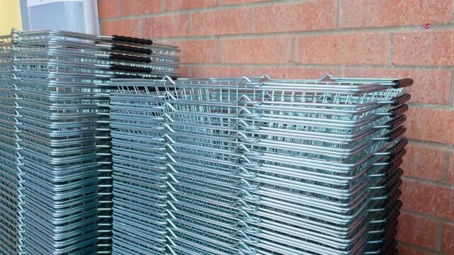 Shopping basket stacked at supermarket entrance. Metal store baskets waiting for shoppers. Grocery shopping equipment for customers. Supermarket exterior with retail baskets near entrance