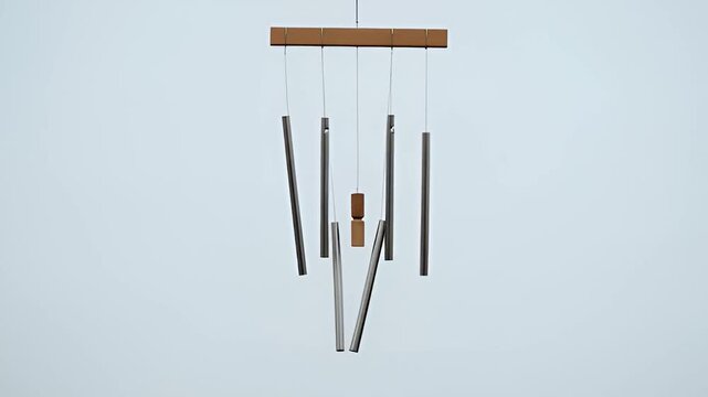 Minimal wind chime background with gentle asynchronous sway against pale sky