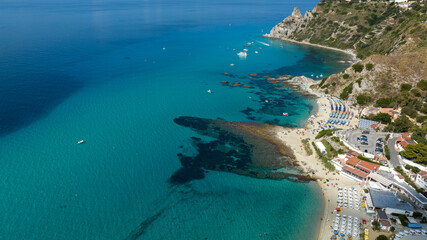 Fototapeta premium Aerial view of Grotticelle beach, located in the municipality of Ricadi, Calabria, Italy. In the background is the promontory of Capo Vaticano, a symbol of the Coast of the Gods. It is a summer day.