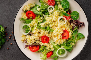 Couscous salad vegetables tomato, onion, green lettuce leaves food preparation tasty snack fresh delicious gourmet food background on the table rustic food top view copy space keto and paleo diet  