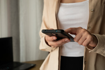 Woman using a mobile phone for work or communication in an office environment with a laptop.