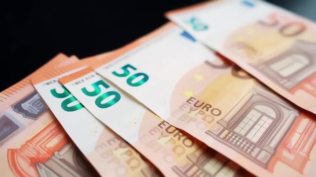 Macro shot of fanned &euro;50 banknotes on a dark background with copy space and shallow focus. Concept for payment, savings, budgeting, and personal finance.