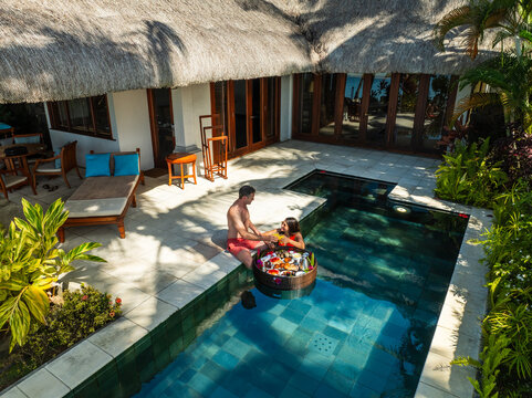 Aerial view of a couple in the pool with a floating tray of food surrounded by lush greenery near the building, Prince Maurice, Flacq District, Mauritius.