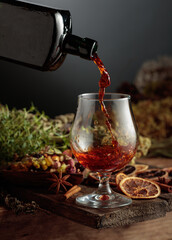 Herbal bitter liqueur is poured from a vintage bottle into a glass.