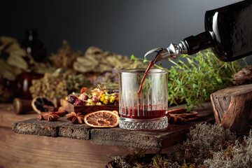 Herbal bitter liqueur is poured from a vintage bottle into a glass.
