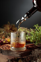 Herbal bitter liqueur is poured from a vintage bottle into a glass.