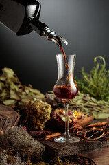 Herbal bitter liqueur is poured from a vintage bottle into a glass.