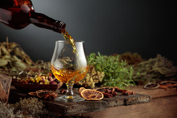 Herbal bitter liqueur is poured from a vintage bottle into a glass.