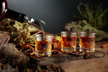 Herbal bitter liqueur is poured from a vintage bottle into a glass.