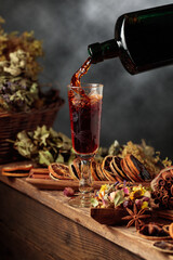 Herbal balm or tincture is poured from a vintage bottle into a glass.