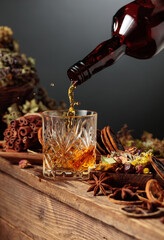 Herbal liquor is poured from a vintage bottle into a glass.