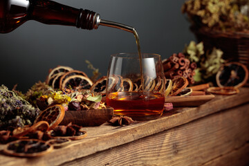 Herbal liquor is poured from a vintage bottle into a glass.