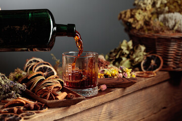 Herbal balm or tincture is poured from a vintage bottle into a glass.