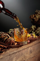 Herbal liquor is poured from a vintage bottle into a glass.