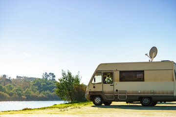 Caravan camping on lake shore with satellite dish on roof