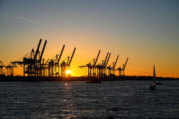 Obraz premium Port of Hamburg, Germany. Silhouettes of cranes in the port at sunset. Industry and transport. Port of Hamburg.