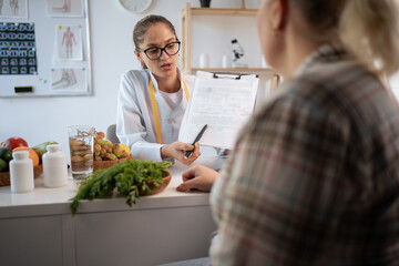 Female nutritionist explaining personalized meal plan to overweight patient during healthcare consultation. dietitian showing nutrition plan