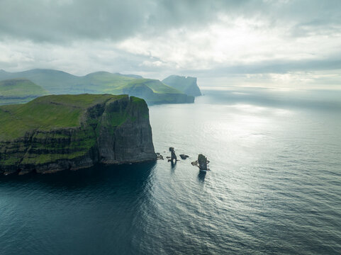 Aerial view of dramatic cliffs plunging into the sea under a brooding sky, highlighting the stark beauty of the coastline, Tjornuvik, Streymoy, Faroe Islands.