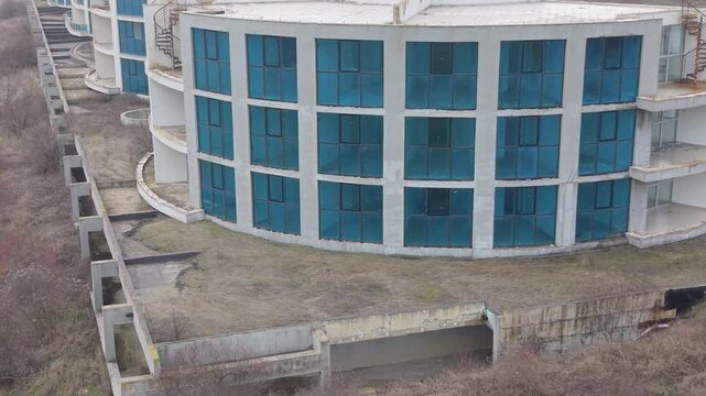 High angle aerial capture of deserted architecture complex surrounded by barren land emphasizing isolation and unused real estate investment.