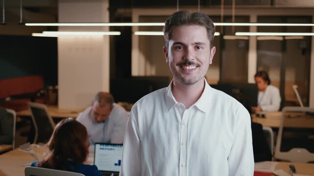Millennial businessman with a moustache smiling in a modern office