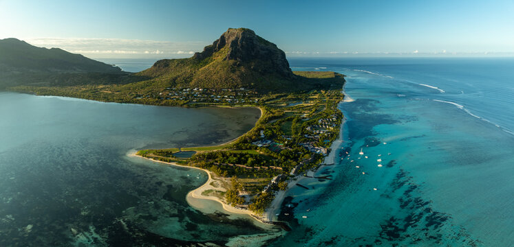 Aerial view of the majestic Le Morne Brabant mountain meeting the turquoise sea, as boats dot the coastline, Le Morne, Riviere Noire District, Mauritius.