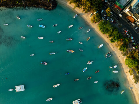 Aerial view of boats scattered across the turquoise waters meeting the sandy beach near Grand Baie, Riviere du Rempart District, Mauritius.