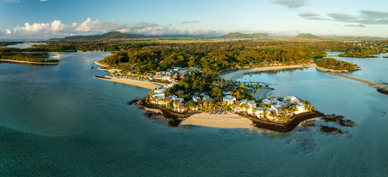 Aerial view of a luxurious coastal resort with white buildings nestled among lush green trees, fringed by golden sands and the turquoise waters, Shangri La, Trou d'Eau Douce, Mauritius.