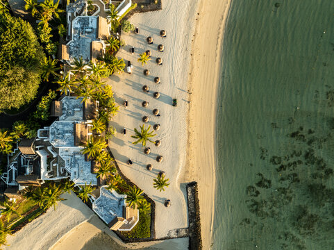Aerial view of the beachside resort, where the white sand meets the clear turquoise water, palm trees sway gently in the breeze, Shangri La, Trou d'Eau Douce, Mauritius.
