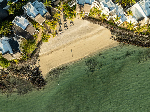 Aerial view of a golden beach meeting the turquoise sea, flanked by luxurious villas and swaying palms, Shangri La, Trou d'Eau Douce, Mauritius.