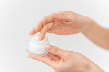 スキンケアプロセス。ジャー容器からクリームをすくっている手元。
