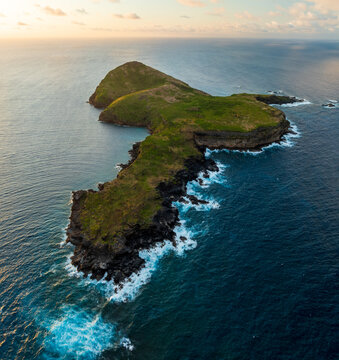 Aerial view of Coin de Mire island, a verdant jewel amidst the turquoise embrace of the Indian Ocean, with crashing waves against its jagged coastline, Coin De Mire, Mauritius.