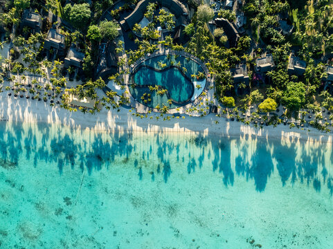 Aerial view of turquoise waters meeting the sandy shore, fringed by verdant trees and circular pools, a tropical dream unfolds, Triolet, Pamplemousses, Mauritius.