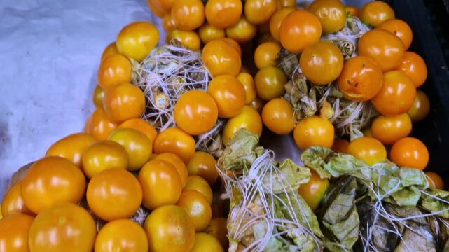A vibrant pile of ripe golden berries (physalis) with delicate papery husks. The close-up showcases the smooth, orange texture of the fruit against a clean background.