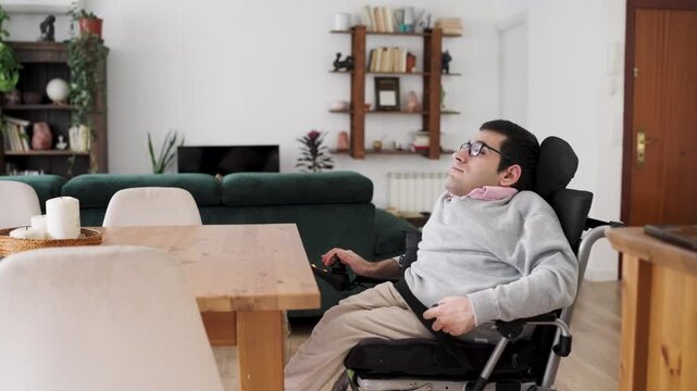 Man with a physical condition using a motorized wheelchair to move through his modern, bright living room, demonstrating daily independent living