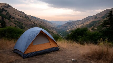 Obraz premium A camping tent is set on a dry grassy hillside overlooking a vast mountain valley during dawn