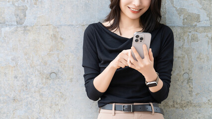 壁の前でスマートフォンを操作する若い女性のポートレート, Young woman...
