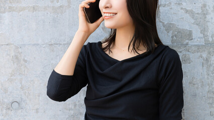 壁の前でスマートフォンで通話をする若い女性のポートレート, Young woman...