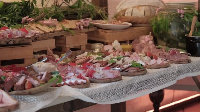 Gourmet charcuterie and cold cut spread arranged on a rustic buffet table with lace tablecloth.