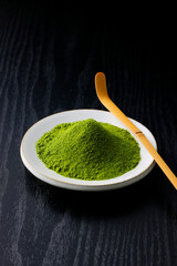 黒背景の木目に映える鮮やかな日本の抹茶の粉末　Vibrant Japanese matcha green tea powder on dark wood background