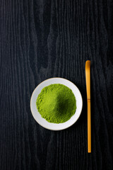黒背景の木目に映える鮮やかな日本の抹茶の粉末　Vibrant Japanese matcha green tea powder on dark wood background