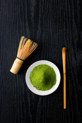 黒背景の木目に映える鮮やかな日本の抹茶の粉末　Vibrant Japanese matcha green tea powder on dark wood background
