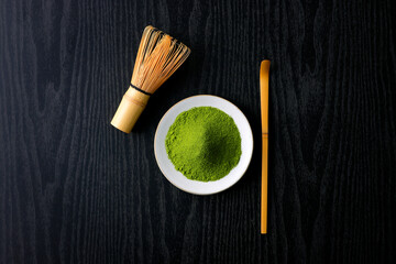 黒背景の木目に映える鮮やかな日本の抹茶の粉末　Vibrant Japanese matcha green tea powder on dark wood background