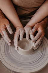male and female hands of a potter at a pottery wheel