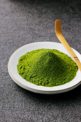 グレーのモダンな背景に映える鮮やかな日本の抹茶の粉末　Premium authentic Japanese matcha powder on a minimalist grey texture background