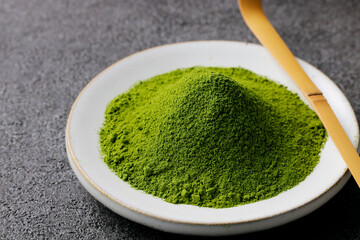 グレーのモダンな背景に映える鮮やかな日本の抹茶の粉末　Premium authentic Japanese matcha powder on a minimalist grey texture background