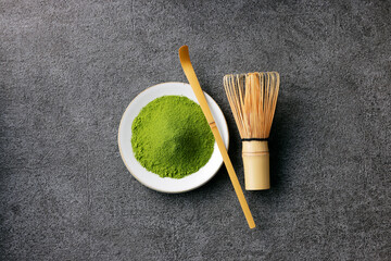 グレーのモダンな背景に映える鮮やかな日本の抹茶の粉末　Premium authentic Japanese matcha powder on a minimalist grey texture background
