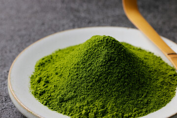 グレーのモダンな背景に映える鮮やかな日本の抹茶の粉末　Premium authentic Japanese matcha powder on a minimalist grey texture background