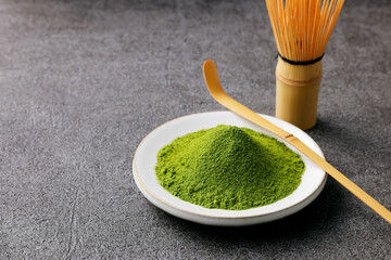 グレーのモダンな背景に映える鮮やかな日本の抹茶の粉末　Premium authentic Japanese matcha powder on a minimalist grey texture background